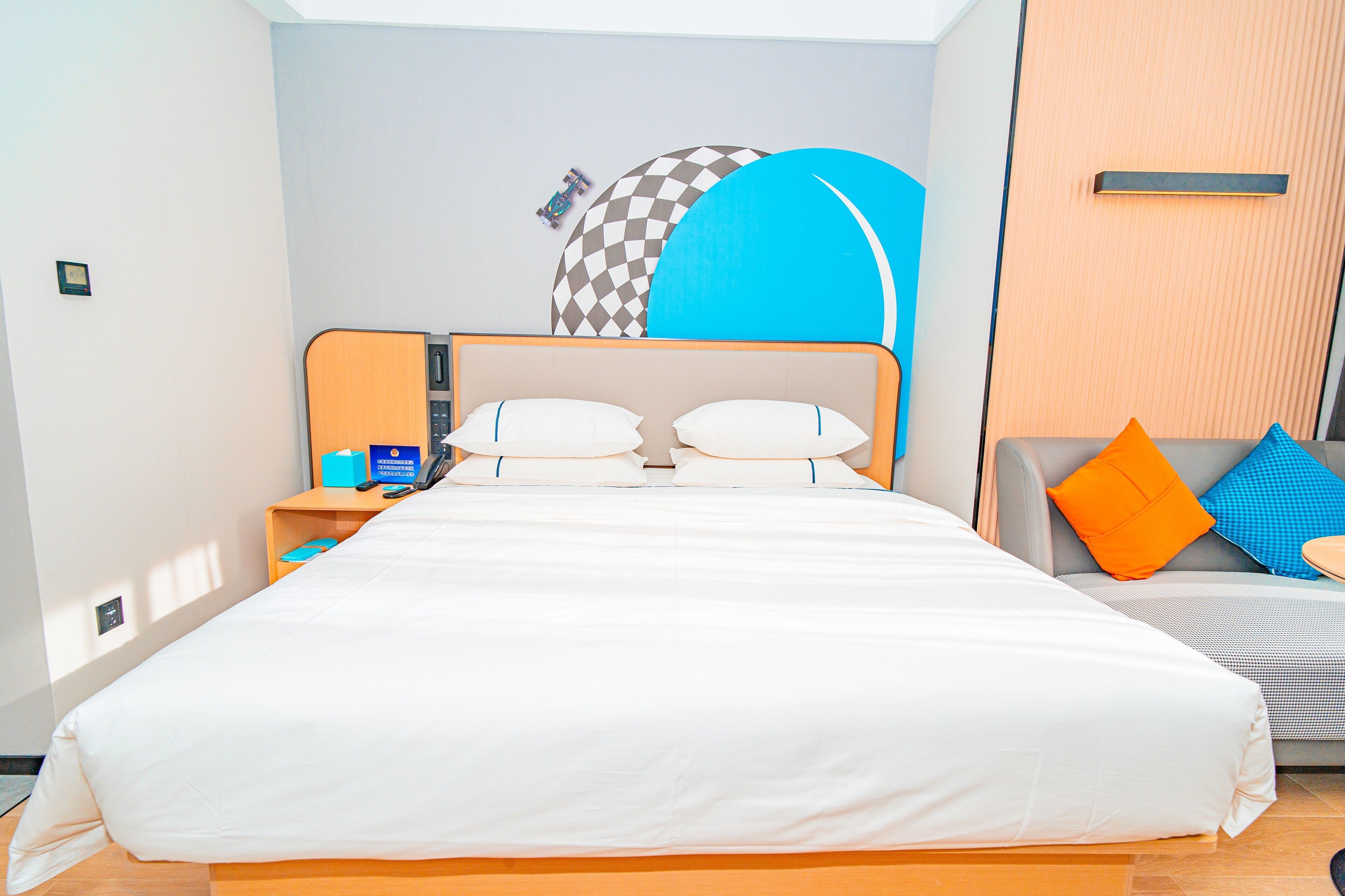 Una habitación de hotel con una cama grande, un escritorio con teléfono y un sofá con cojines de colores.