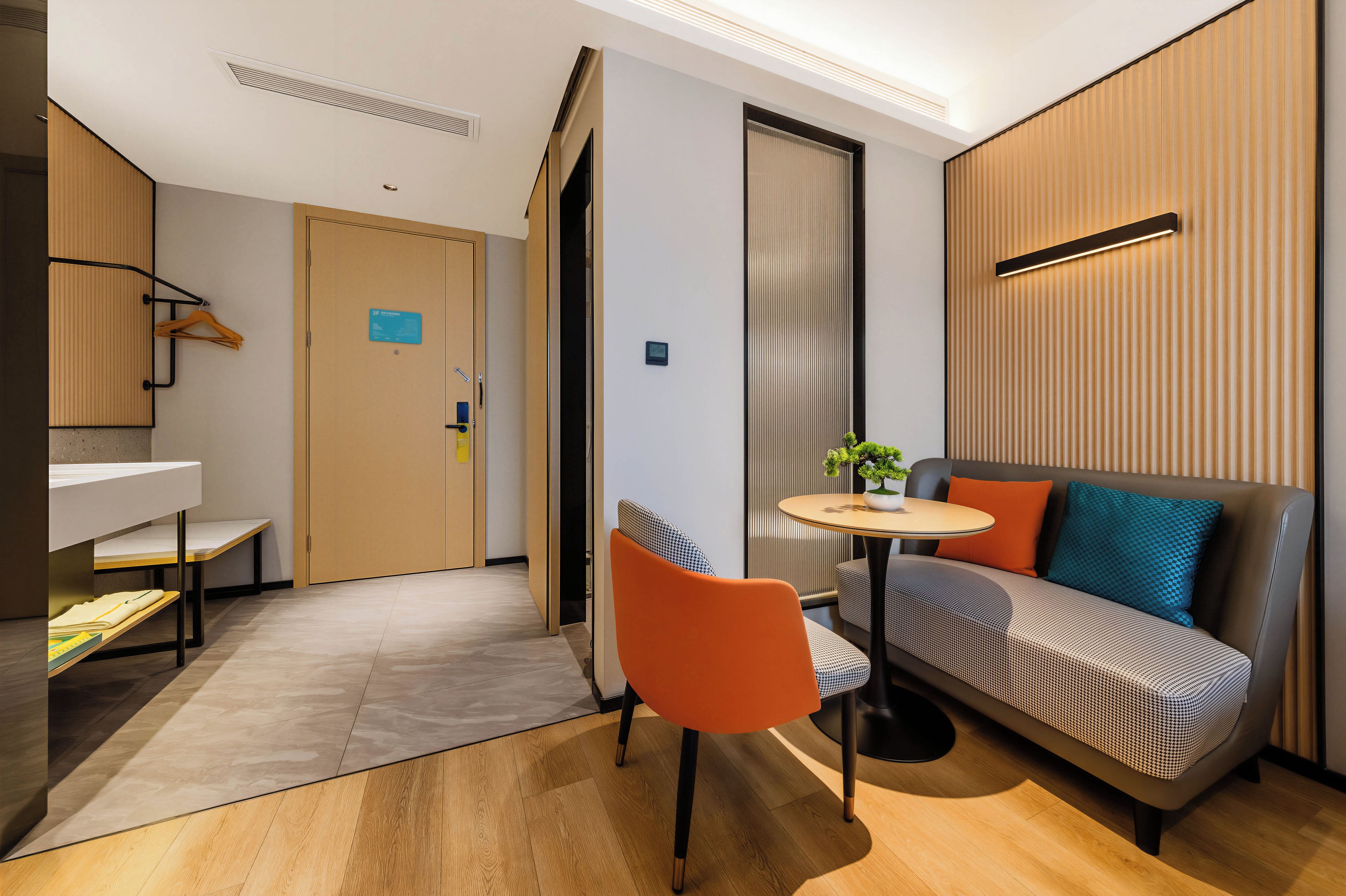 A modern hotel room with a sofa, a small round table, a chair, and a bed.