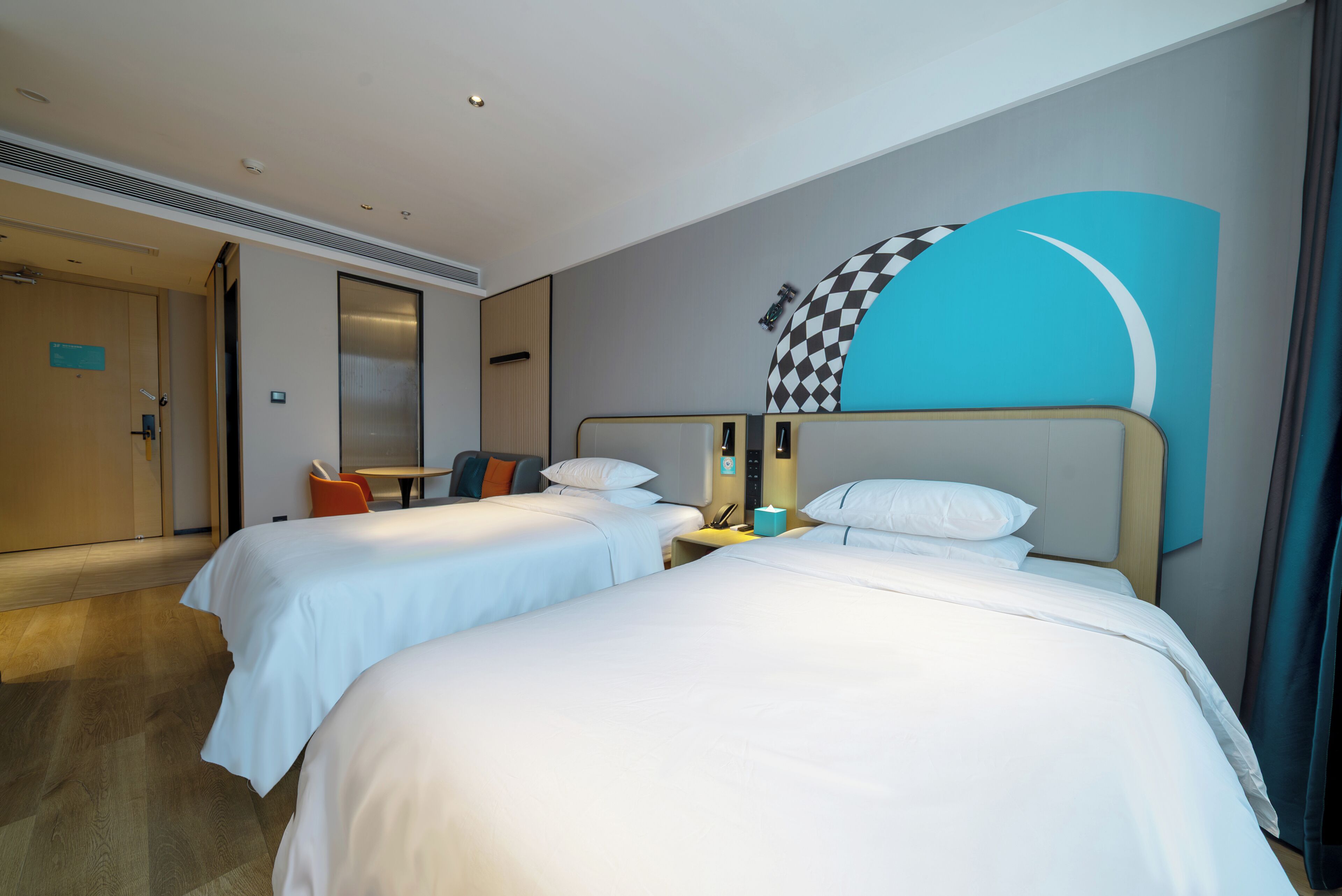 Ein Hotelzimmer mit zwei Betten, einem Schreibtisch, einem Sessel und einer großen Wandmalerei.
