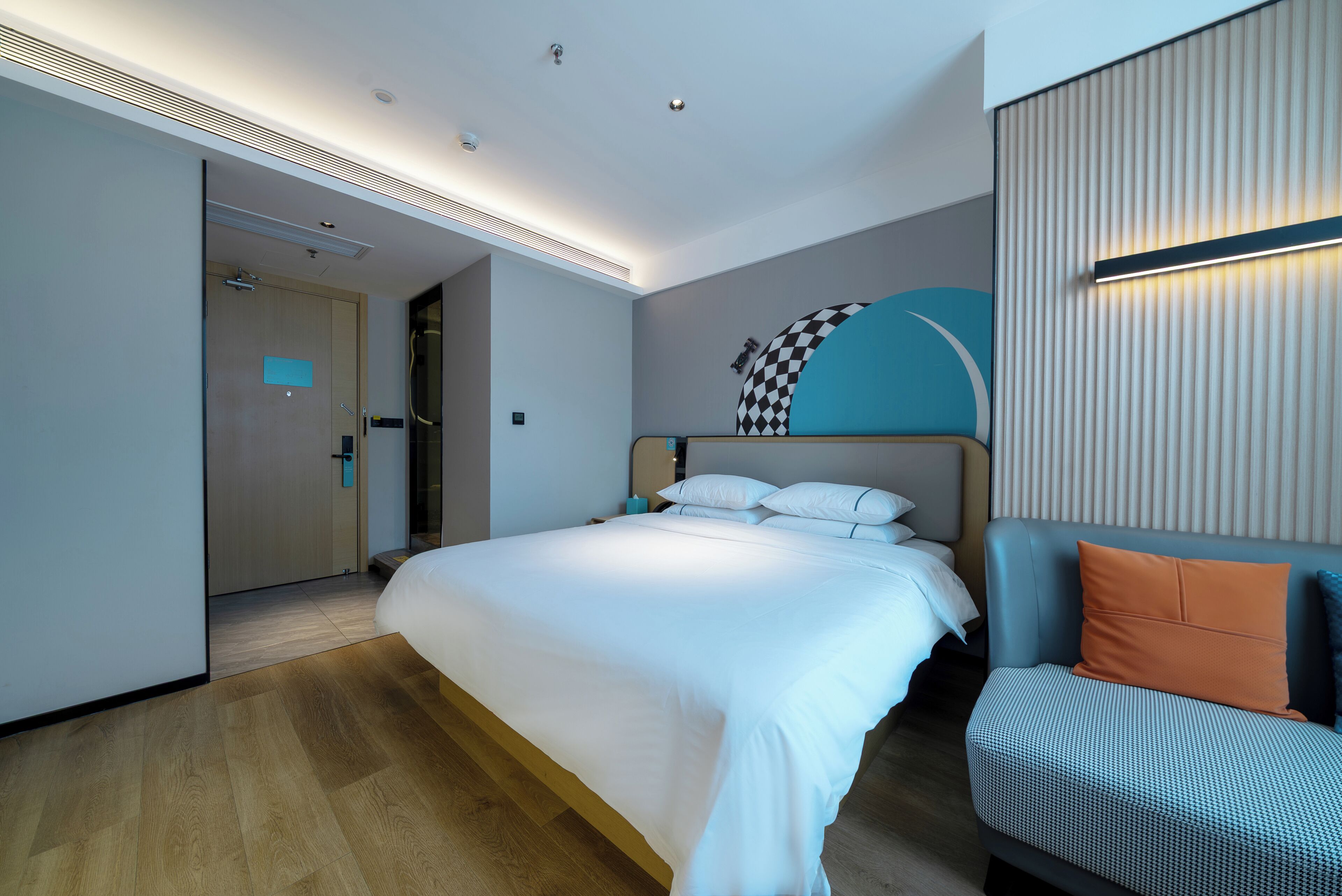 Ein modernes Hotelzimmer mit einem großen Bett, einer Couch und einer Wandleuchte.