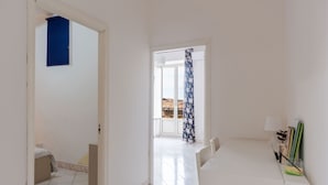 Una habitación con un escritorio blanco, una silla y una cama con cortina azul.