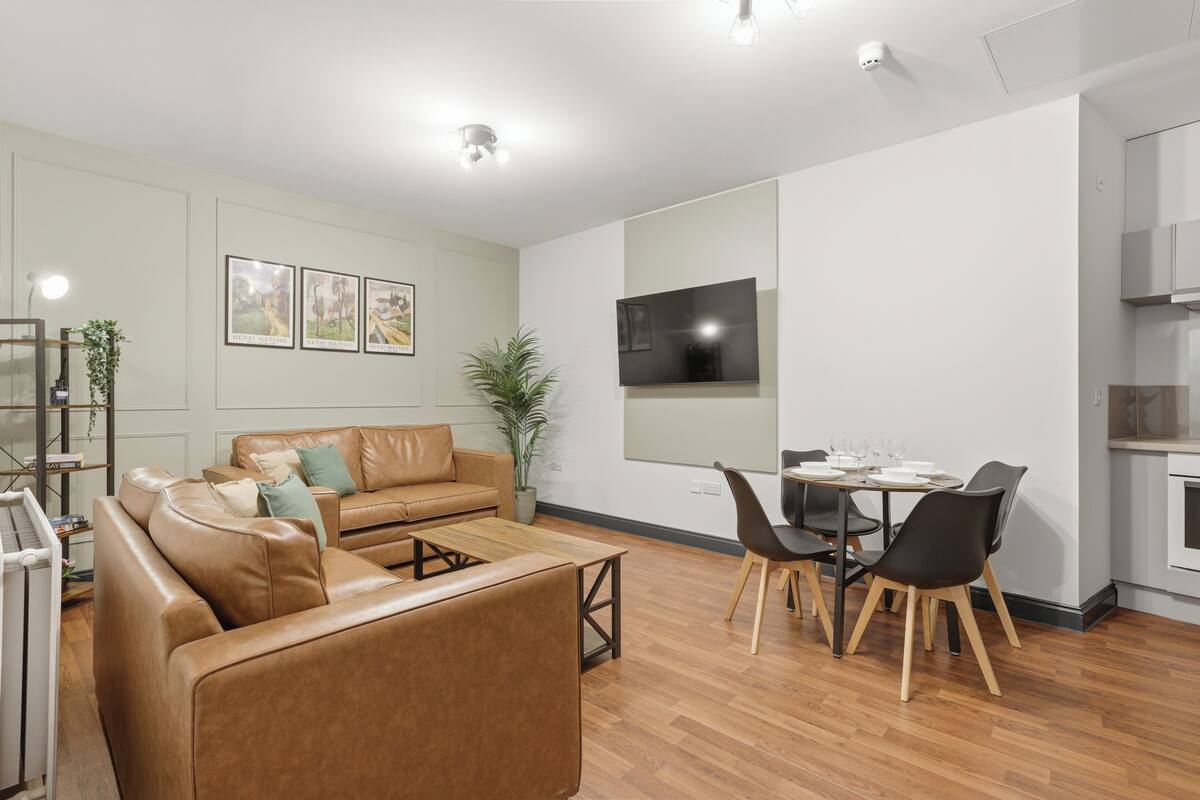 Una sala de estar moderna con sofá, mesa de centro y comedor con sillas y televisor.