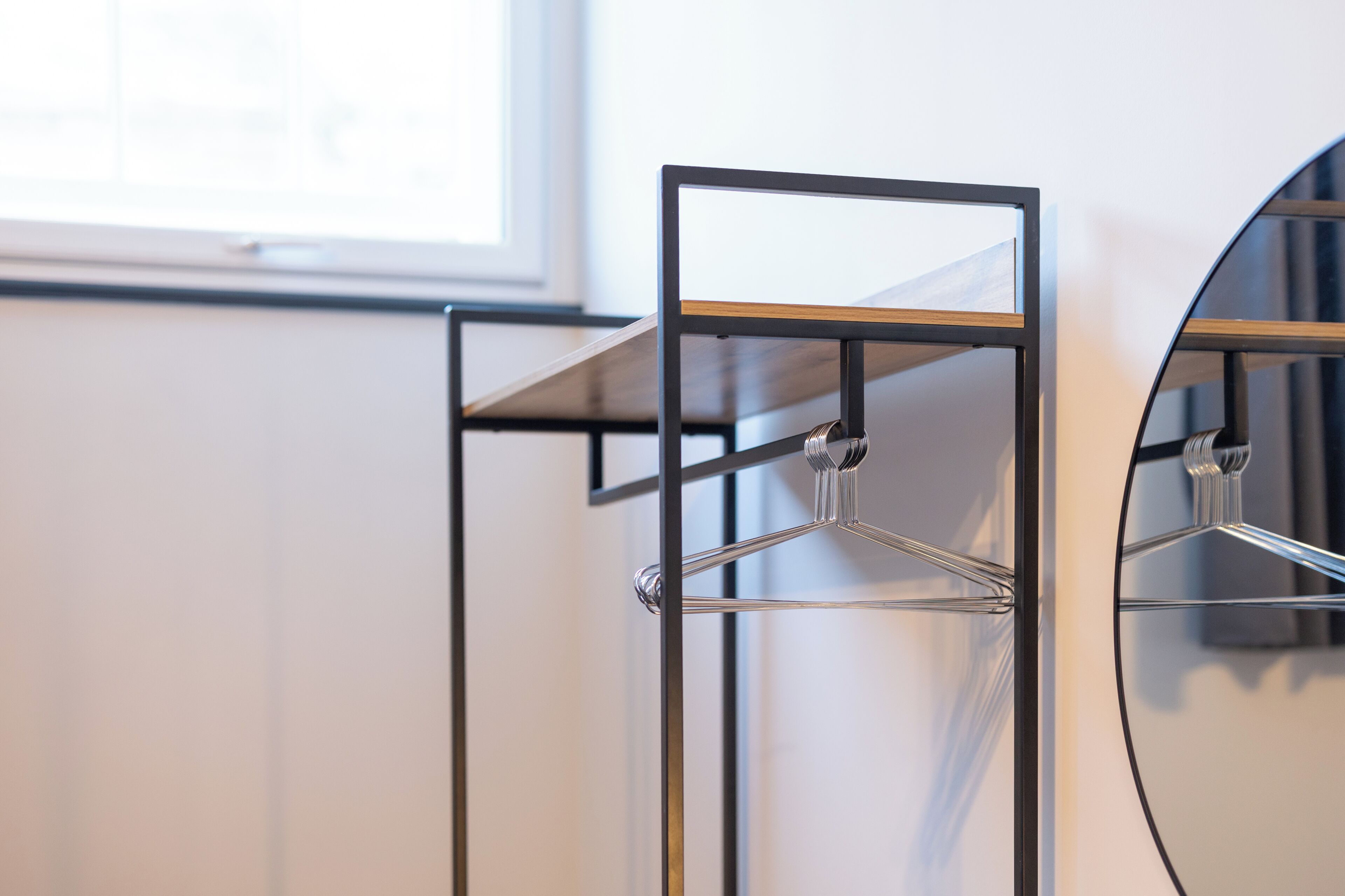 A metal rack with a mirror and a wooden shelf, likely part of a room's decor.