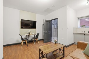 Un espacio habitable moderno con comedor, sofá, televisor montado en la pared y área de cocina.