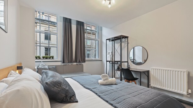 Camera d'albergo moderna con un ampio letto, una scrivania, uno specchio e vista sulla città attraverso ampie finestre.