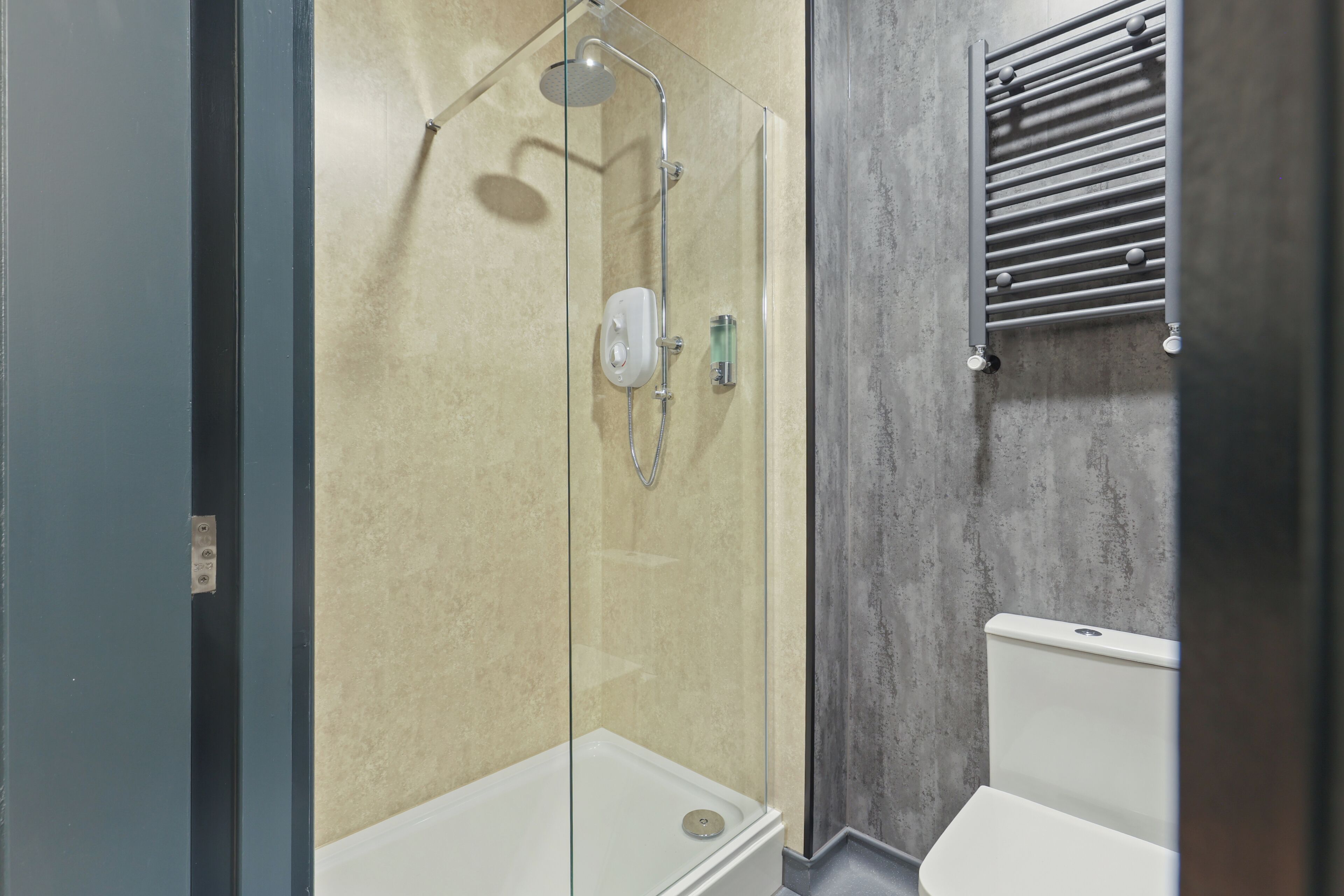 A modern bathroom with a glass-enclosed shower, a toilet, and a towel rack.