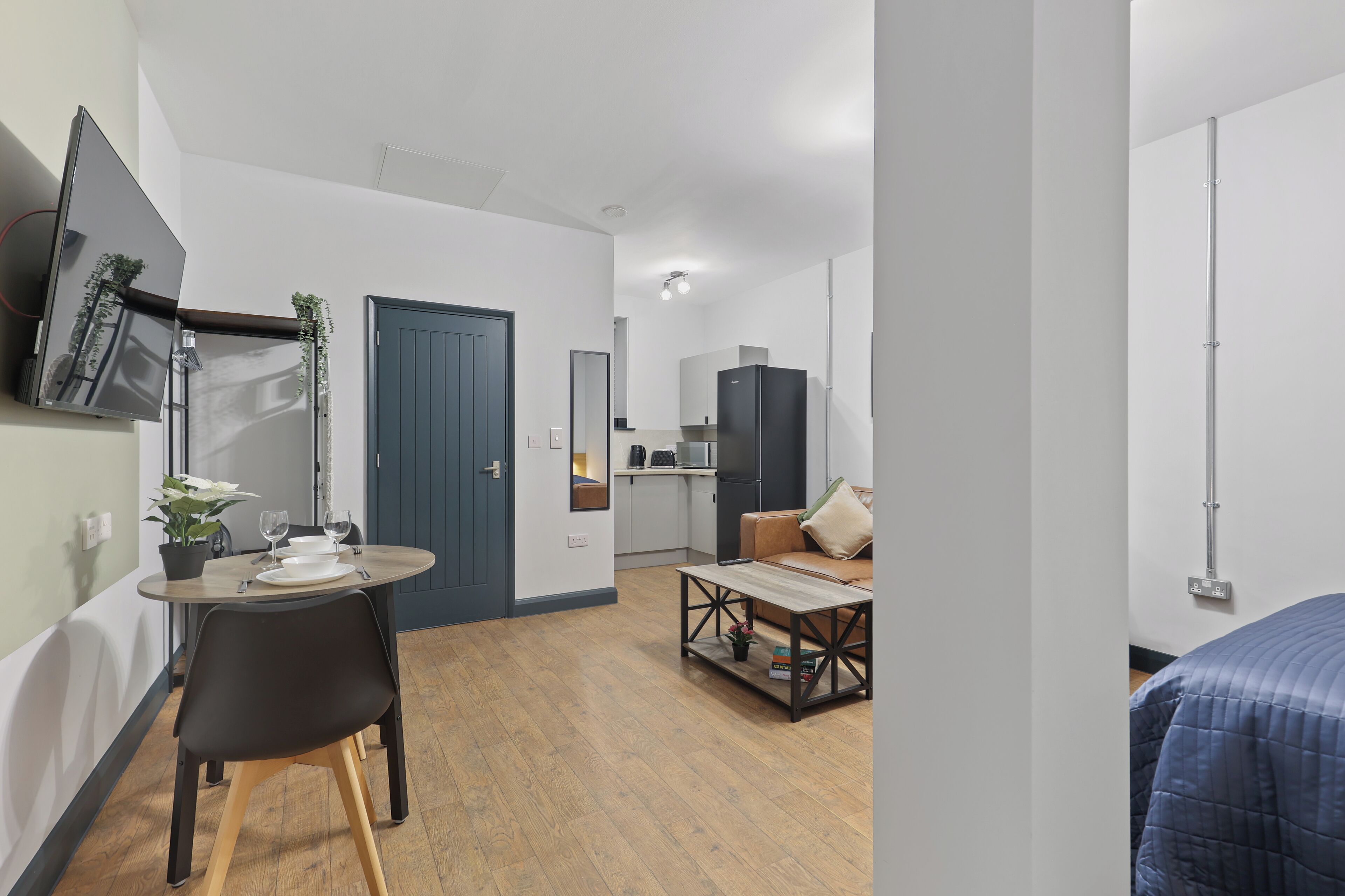 A modern apartment with a dining area, a living room, and a kitchenette.