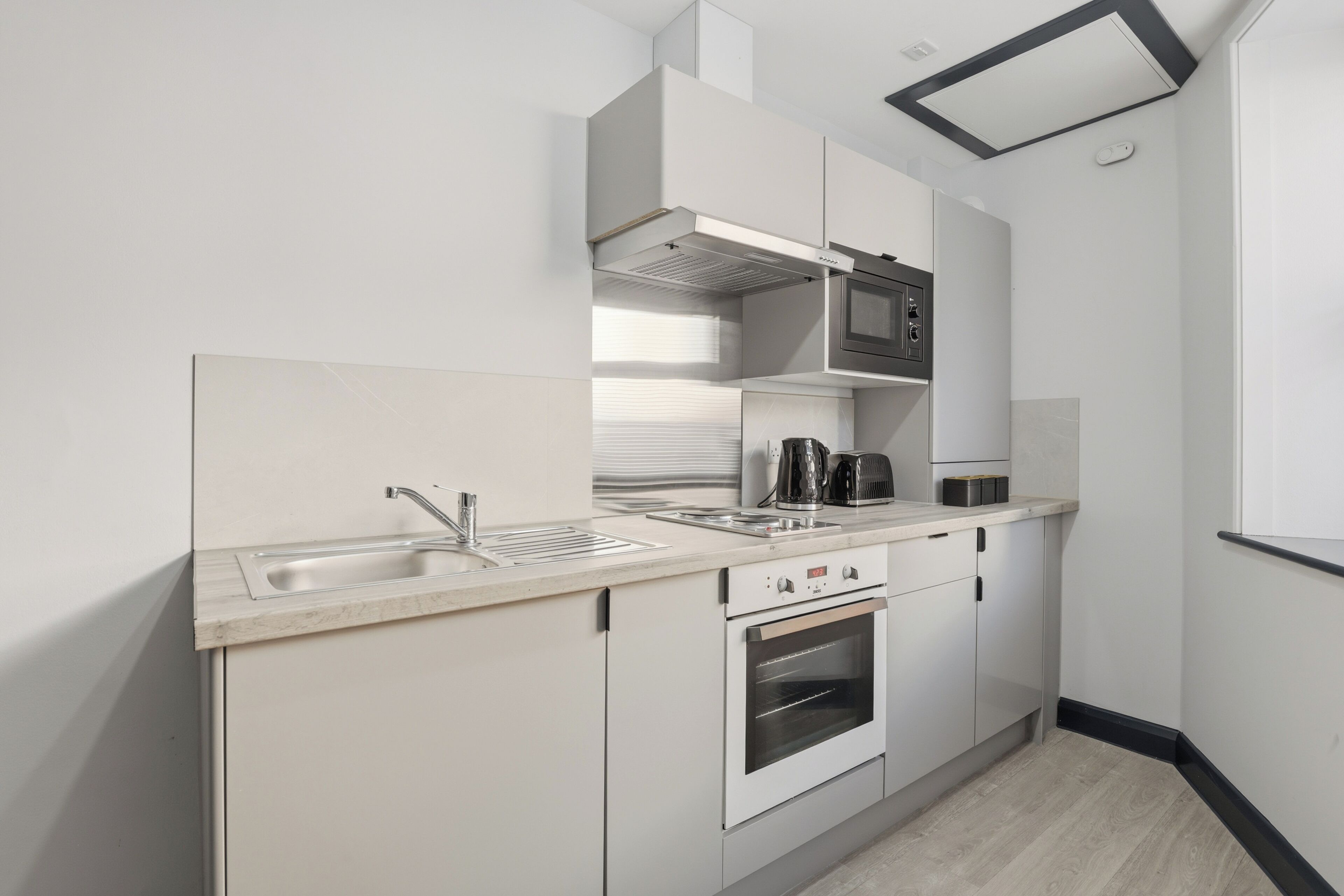 Una cocina moderna con horno empotrado, microondas y cafetera.
