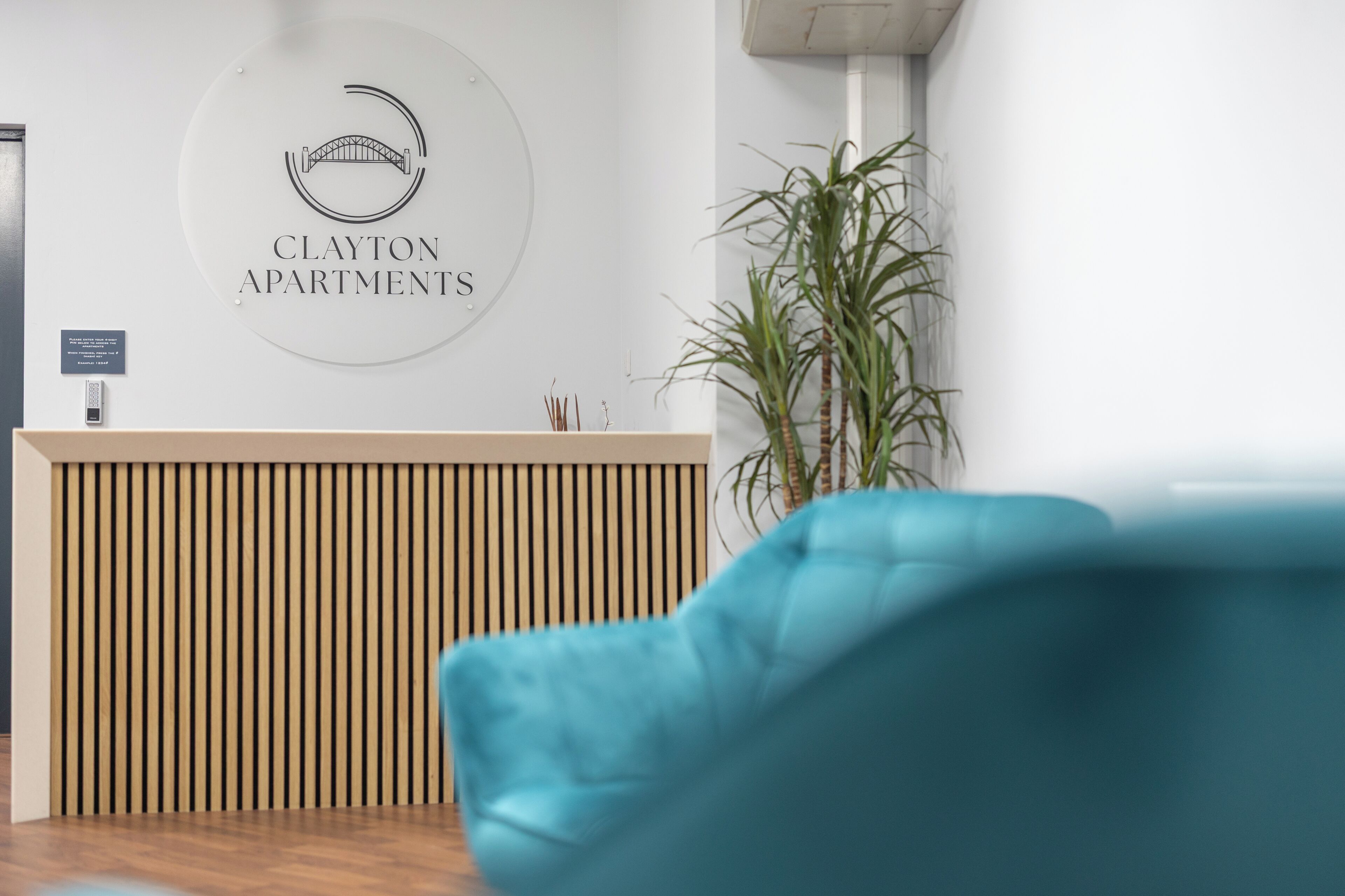 Una recepción con un logotipo, una planta y una silla azul.