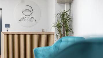 Una recepción con un logotipo, una planta y una silla azul.