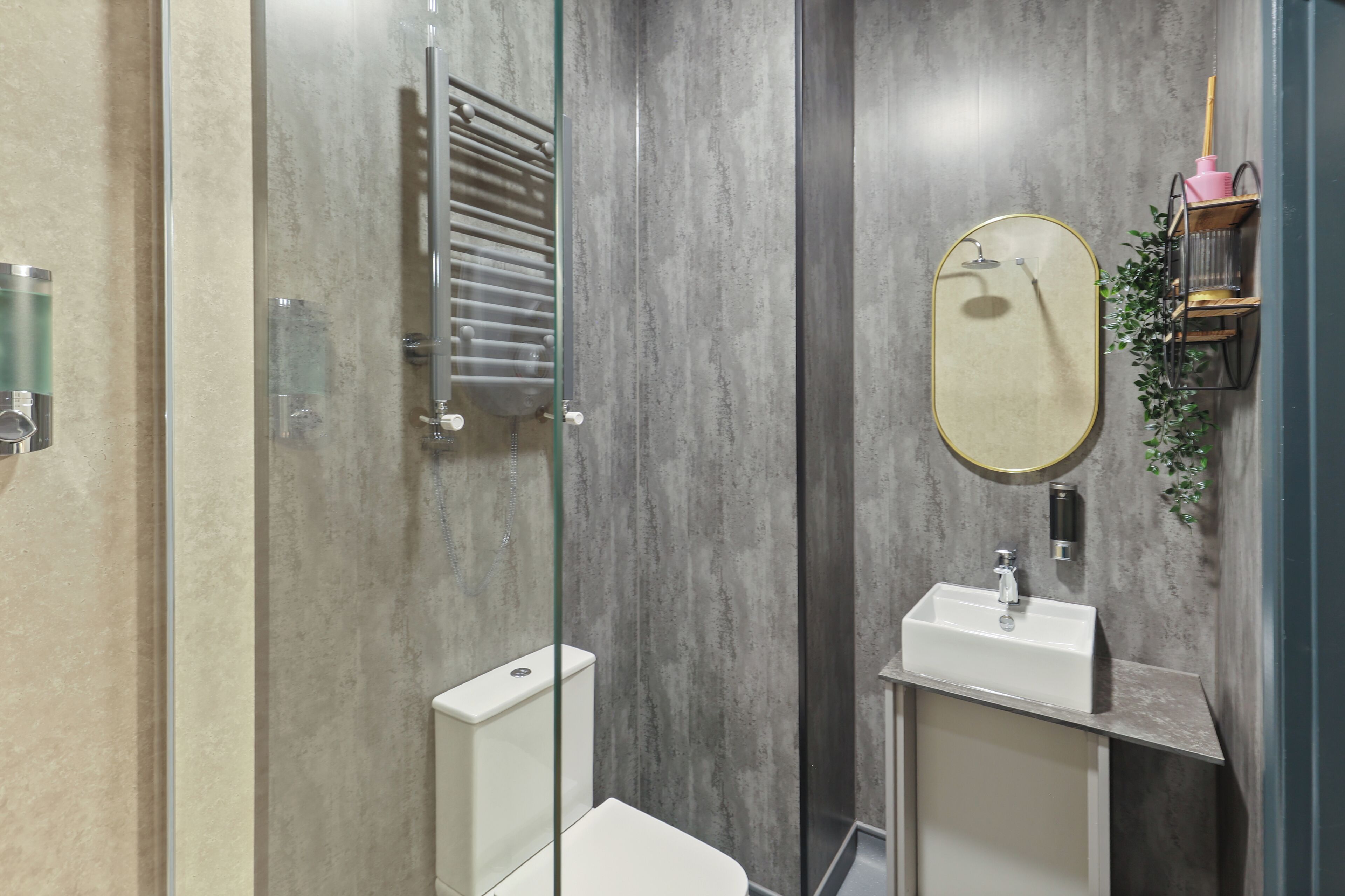 A modern bathroom with a glass shower enclosure, a white toilet, and a sink with a mirror.