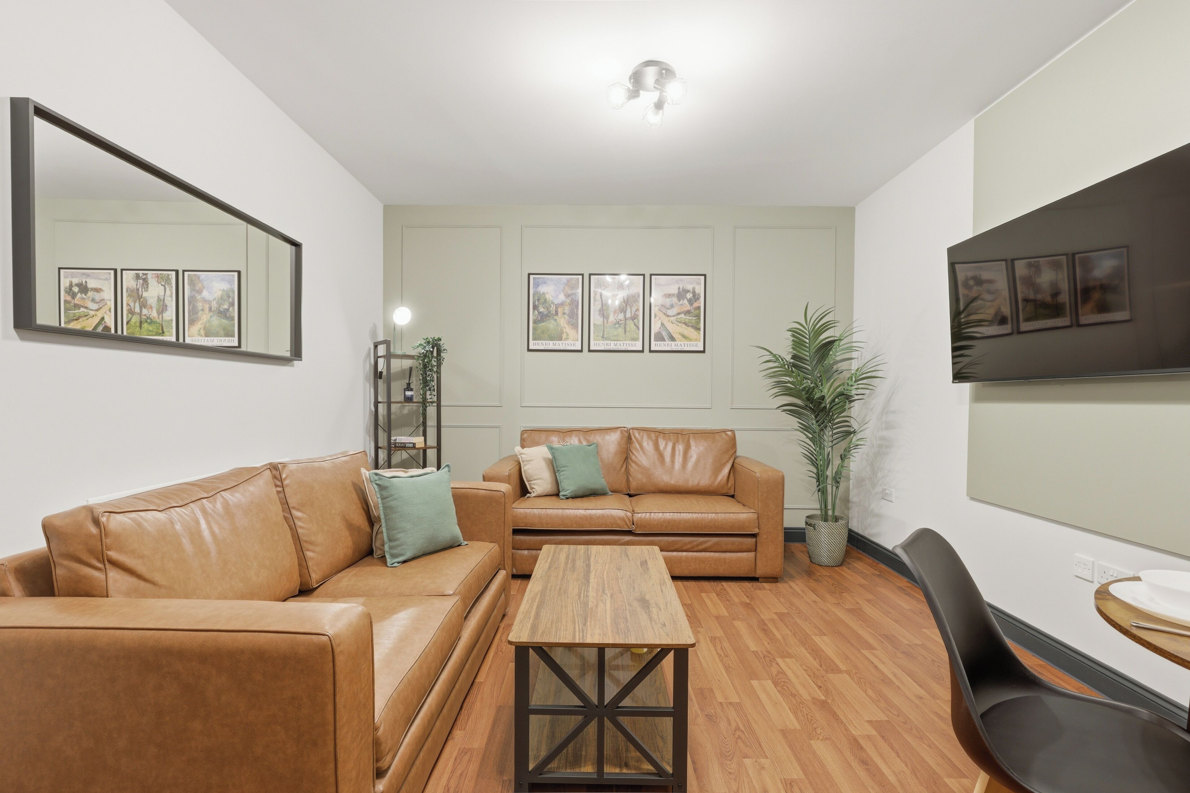 A modern living room with two leather sofas, a wooden coffee table, and a dining area with a chair and table.