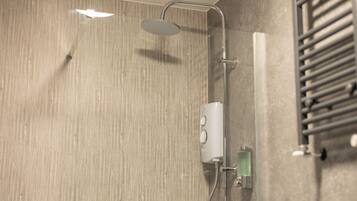 A modern shower with a handheld showerhead, a wall-mounted control panel, and a glass-enclosed soap dispenser.