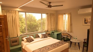 A bedroom with a large bed, a desk, a chair, and a small table with two bottles. - Hotel Spotlight  (Chatrapur)