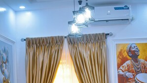 A dining area with a table and chairs, a chandelier, and curtains. - La Veda Manor Luxury Apartment (Ibadan)