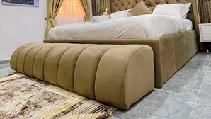 A modern bedroom with a large bed, a headboard, and a decorative rug. - La Veda Manor Luxury Apartment (Ibadan)