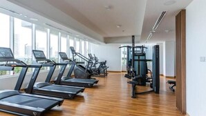 A gym with treadmills, elliptical machines, and a weight machine. - High floor 1BR vacation home with terrace (Dubai)