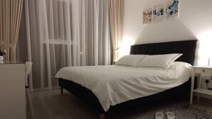 A bedroom with a bed, a nightstand, a desk, a chair, and a pair of slippers on the floor. - High floor 1BR vacation home with terrace (Dubai)