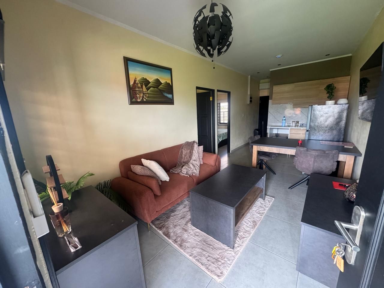A modern living room with a sofa, coffee table, and a dining area with a kitchen counter.
