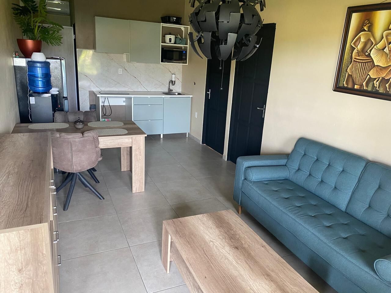 Un salon moderne avec un canapé bleu, une table basse en bois et un coin repas comprenant une table et des chaises.