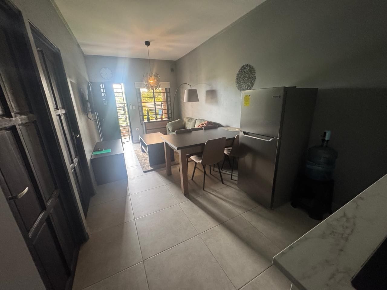 Een keuken met een eettafel, stoelen, een koelkast en een waterdispenser.