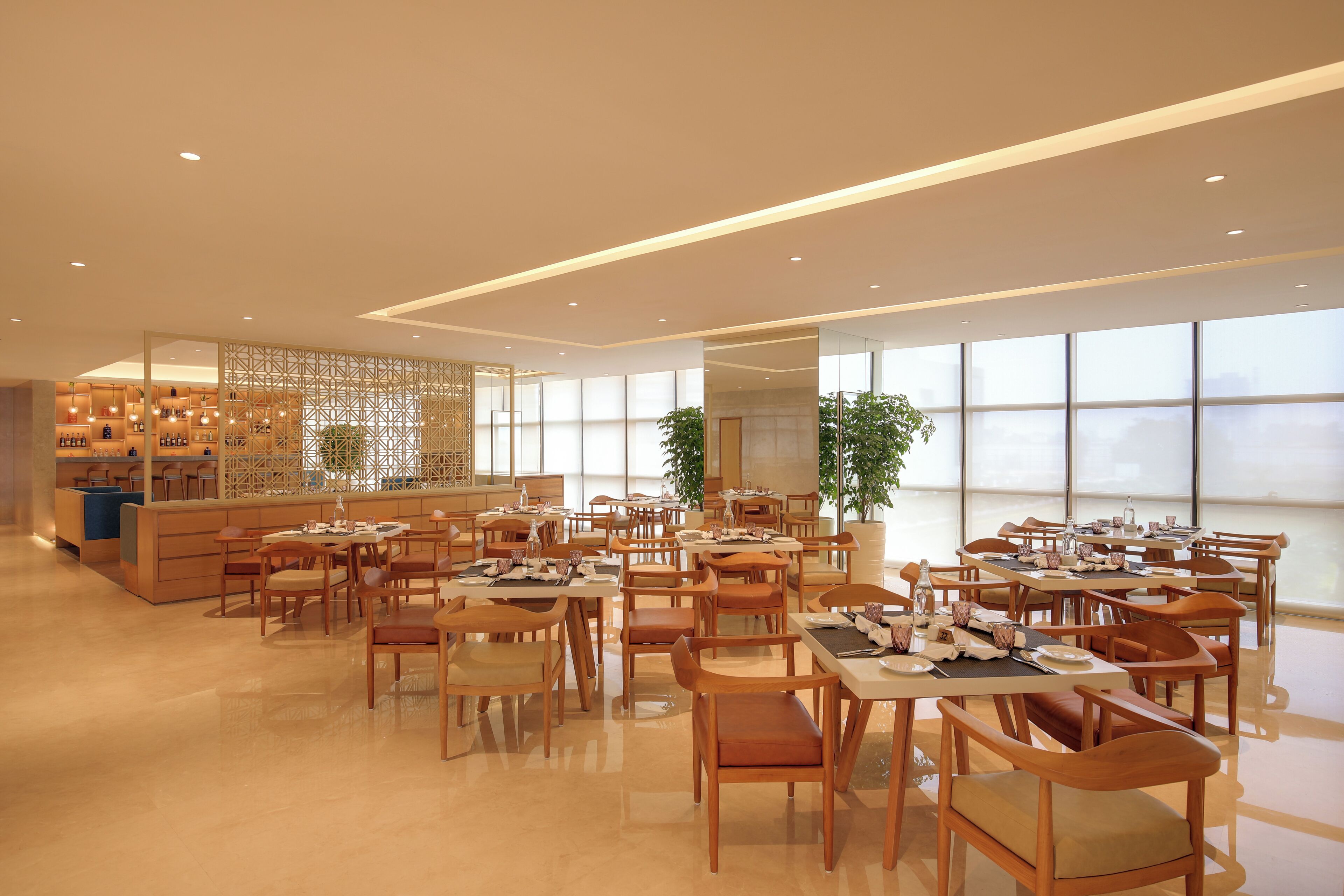 A spacious dining area with multiple tables and chairs, a reception desk, and large windows providing natural light.