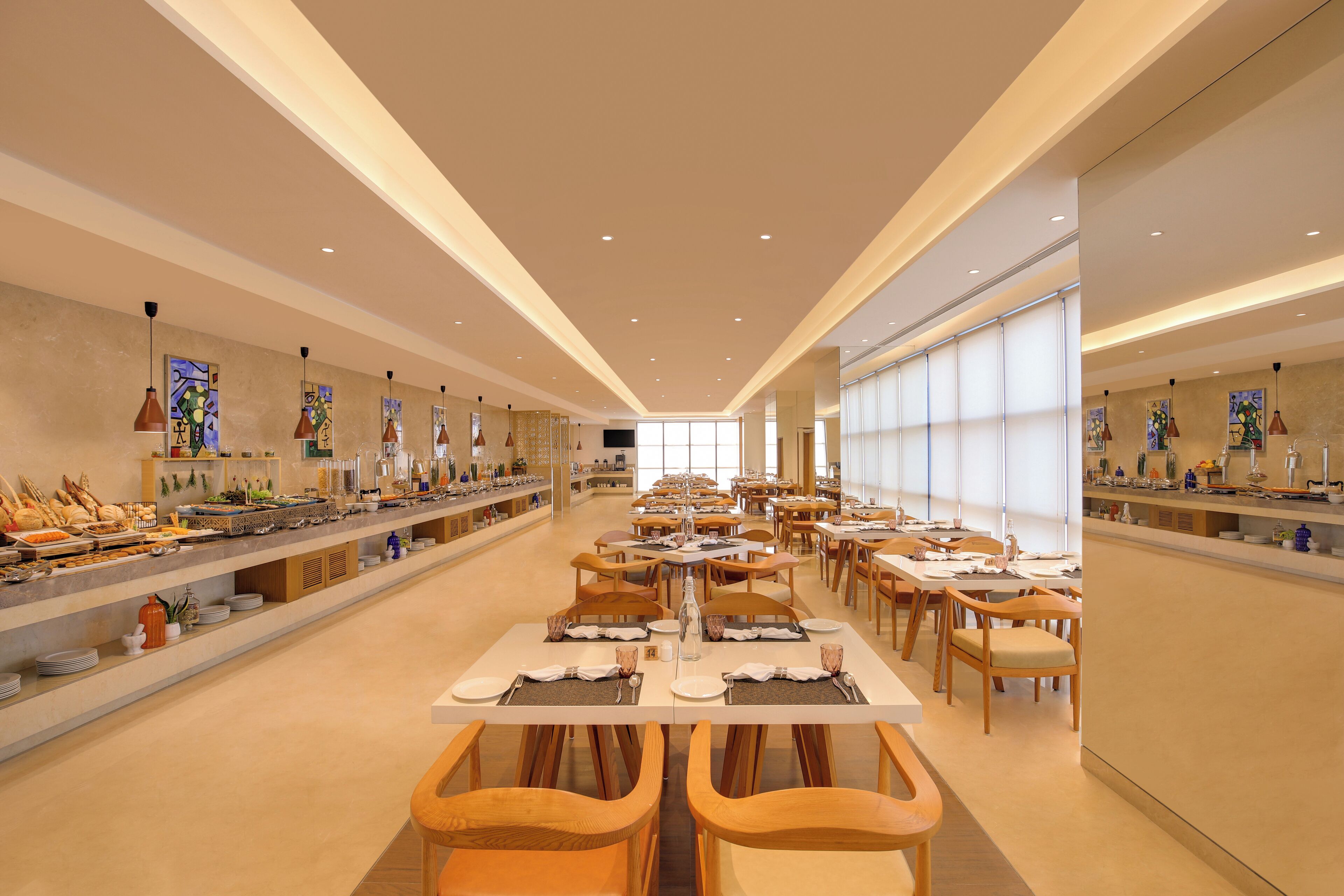 A spacious dining area with multiple tables and chairs, a buffet on the left, and large windows on the right.