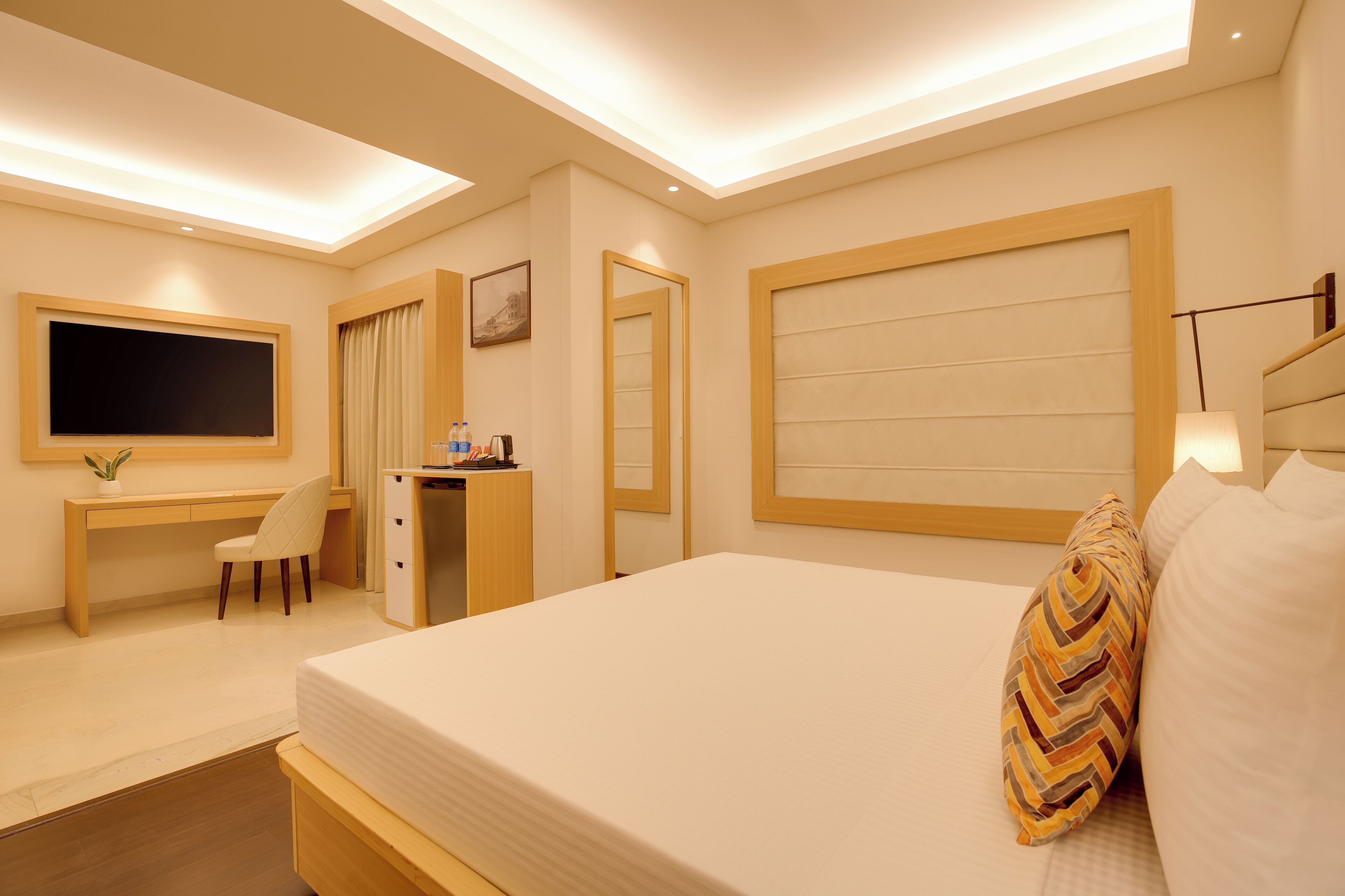 Een moderne hotelkamer met een groot bed, een bureau, een stoel, een televisie en een kledingkast.