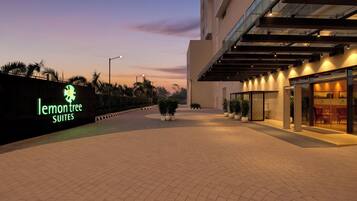 Entrada de hotel con un letrero que dice 'lemon tree suites' y un área exterior cubierta con asientos.