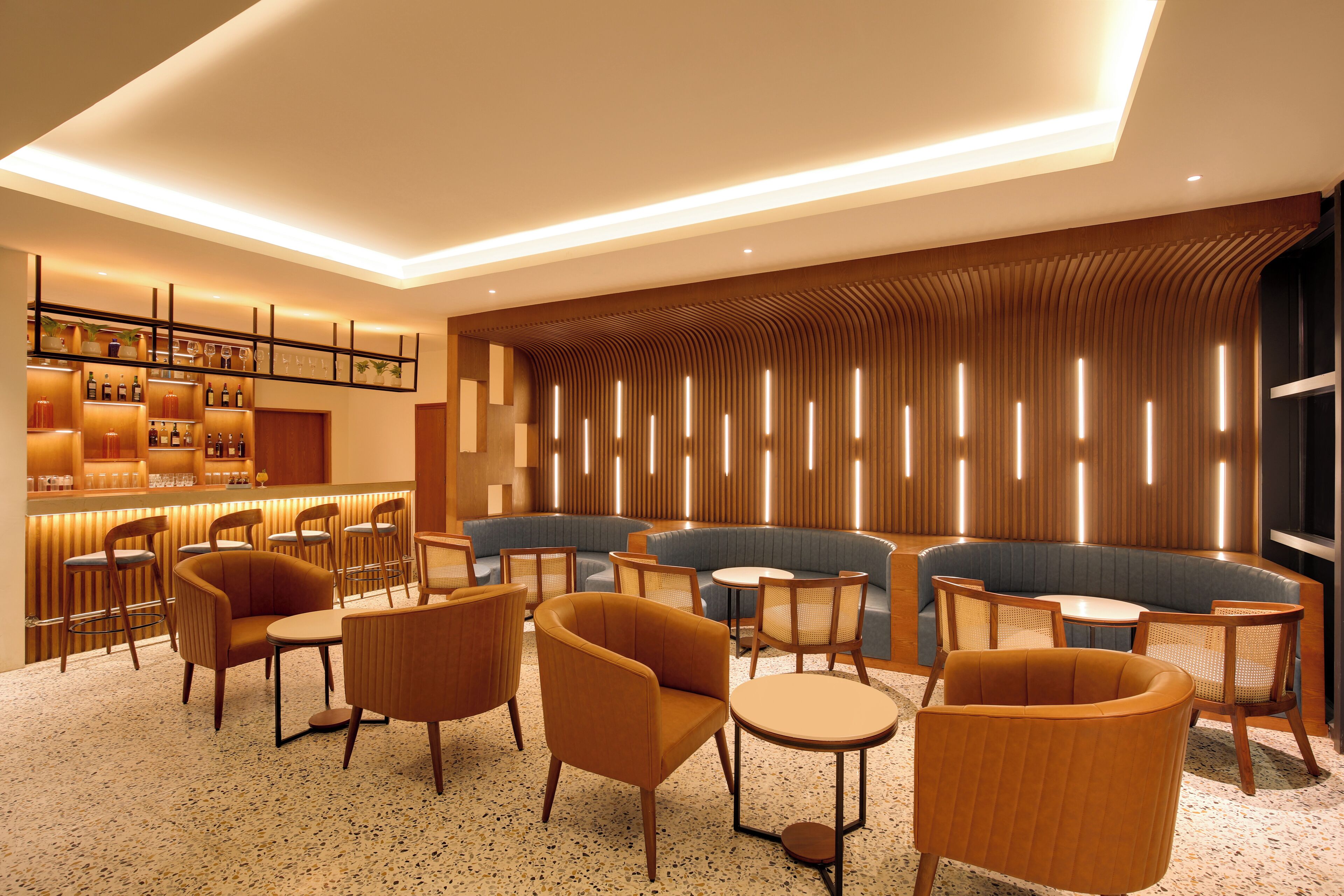 A modern lounge area with seating, a bar, and a decorative wall.