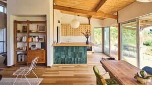 Una cucina moderna con soffitto in legno, isola verde e un'ampia finestra.