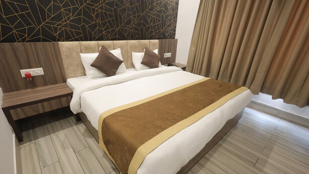 Una camera d'albergo con un letto grande, una testiera in legno, un comodino e un design moderno delle pareti.