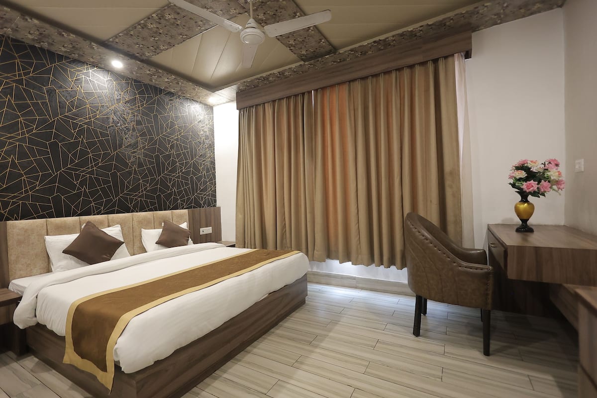 Una habitación de hotel con una cama grande, un escritorio, una silla y una ventana con cortinas.