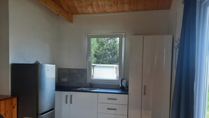 Eine kleine Küche mit Kühlschrank, Fenster und Spüle.
