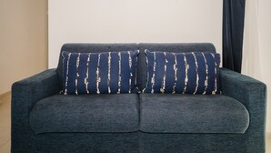 A dark blue sofa with two patterned cushions against a plain wall. - Comfort Quadruple Room with Mountain View, Wi-Fi and Air Conditioning (Calangianus)