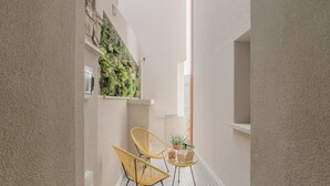 Un couloir étroit avec deux chaises jaunes, une petite table sur laquelle est posée une plante, et un jardin vertical sur le mur.