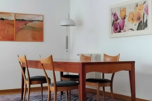 Ein Essbereich mit Tisch, Stühlen, einer Stehlampe und zwei Wandbildern.