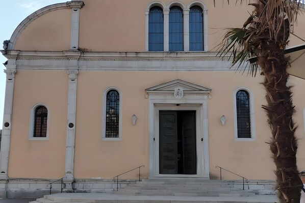 A building with a large arched entrance, a central door, and multiple windows.