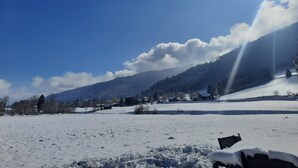 A snowy landscape with a clear sky, a mountain in the background, and a few buildings scattered across the field. - Parc Sonnleiten - Edelhert (Gnesau)