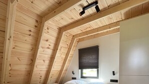 A bedroom with a sloped ceiling, a bed, a window with blinds, a bedside table, and a wardrobe. - Parc Sonnleiten - Edelhert (Gnesau)