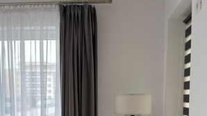 Une pièce avec une grande fenêtre, un lampadaire et un rideau.