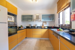 A modern kitchen with wooden cabinets, a microwave, a stove, and a sink. - Lovely three bedroom villa perfectly located in Kalkan (kalkan)