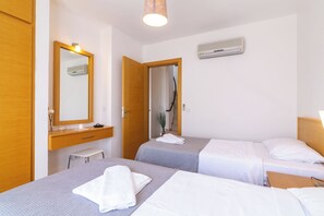 A hotel room with two beds, a wooden wardrobe, a mirror, a small table, and an air conditioning unit. - Lovely three bedroom villa perfectly located in Kalkan (kalkan)