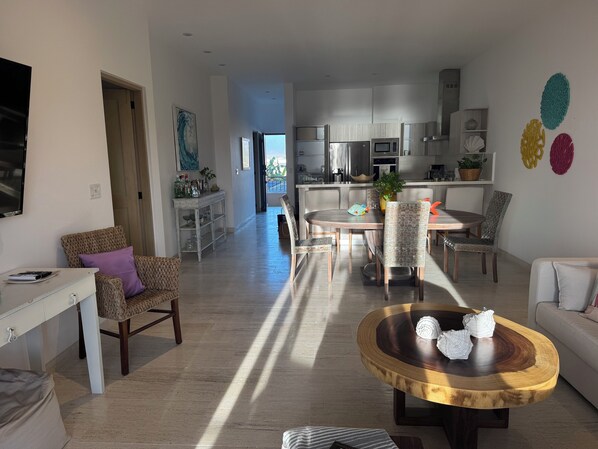 A spacious living area with a dining table, chairs, and a coffee table.
