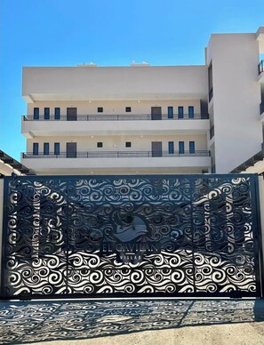 A multi-story building with balconies and a decorative metal gate with intricate patterns.