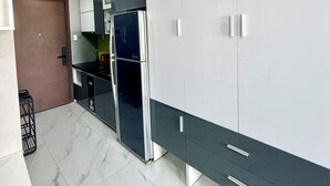 A modern kitchen with a built-in refrigerator, white cabinets, and a marble floor. - Rivergate-High Floor-Ben Thanh -Bui Vien (Ho Chi Minh City)