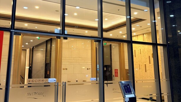 A modern hotel entrance with glass doors, a digital keycard reader, and a sign indicating the name 'RiverGate'. - Rivergate-High Floor-Ben Thanh -Bui Vien (Ho Chi Minh City)
