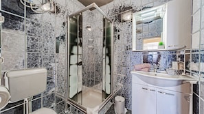 A bathroom with a shower, toilet, sink, and mirror.