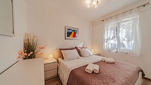 A bedroom with a bed, bedside tables, a nightstand, a window with sheer curtains, and a wall-mounted painting. - Villa Toma by Villas Guide (Orebic)