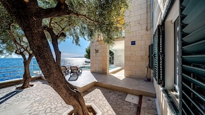 A terrace with a pool, outdoor seating, and a view of the sea.